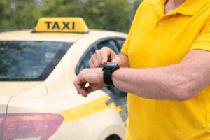Taxi-Fahrer prüft Uhrzeit vor gelbem Taxi – pünktlicher Taxiservice in Kerpen